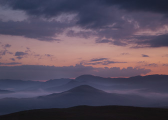 Mystical landscape with hills and fog in the evening