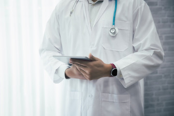 Doctor standing with stethoscope and holding tablet computer. Technology and medical concept.