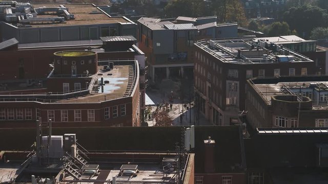 Aerial of a busy shopping street in the UK. The drone flies over buildings to reveal the modern shaded street
