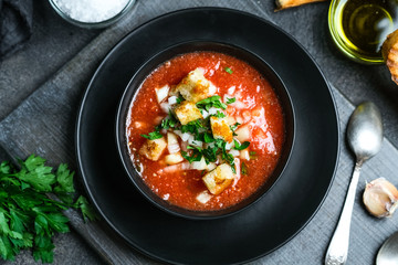 Traditional spanish cold tomato soup gazpacho in a bowl over black slate, stone or concrete background.Top view with copy space.