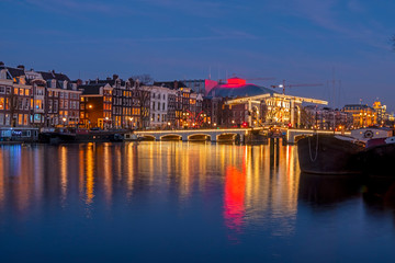 City scenic from Amsterdam at the river Amstel with the Tiny bridge in the Netherlands at night