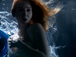 Woman swimming underwater among plastic trash. Girl drowning in sea among garbage. Ecology problem concept