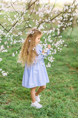 Fototapeta na wymiar Beautiful baby girl in a blooming garden. Spring photo