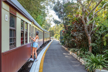 Woman & Kuranda Scenic Railway Train. Tourist train journey across rainforest and jungles in Cairns Australia. Train, train tracks, passenger seats, interior, skyrail, bridge, mountains, landscape.