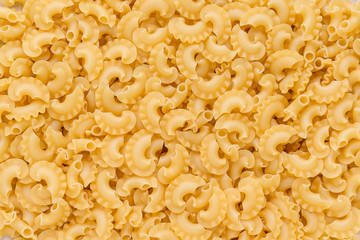 Culinary background from short uncooked pastas. Raw dried pasta texture.