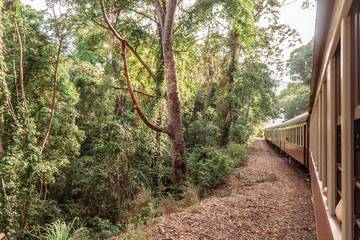 Tourist train journey. Kuranda Scenic Railway Train across rainforest, jungles. Train, train tracks, passenger seats, interior, skyrail, bridge, mountains and landscape.