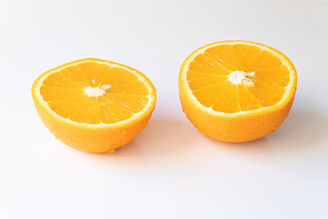 Two halves of fresh orange with drops of water on a white background
