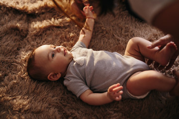portrait of a child 4 months old lying on the bed and looking. Charming child with dark eyes lying...
