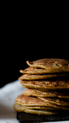 OAT PANCAKES WITH SYRUP ON A BLACK BACKGROUND