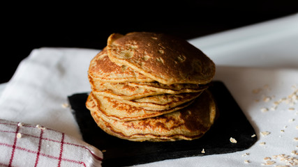 OAT PANCAKES WITH SYRUP ON A BLACK BACKGROUND
