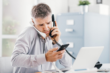 Stressed businessman having multiple calls