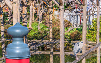 Japanese bridge pillar in the shape of a onion giboshi and crane bird standing on a wooden pergola over the pond of the Kameido Tenjin shrine dedicated to Sugawara no Michizane the deity of studies.