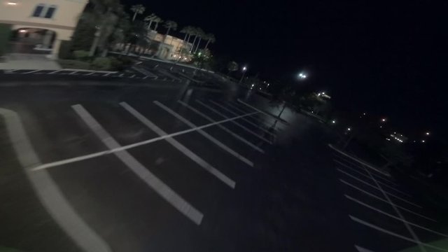An FPV racing drone performing extremely fast and difficult aerial acrobatic maneuvers over an empty hotel lot