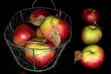 Lot of whole fresh garden apple in basket isolated on black glass