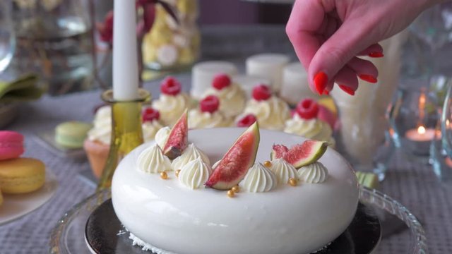 Confectioner Woman is Decorating Delicious French Cake with fig fruit. Concept Bakery chef, Making cake, Bakery business