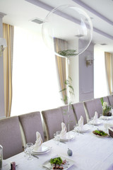 Wedding. Banquet. The chairs and round table for guests, served with cutlery, flowers and crockery and covered with a tablecloth