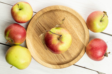 Group of six whole fresh garden apple on wooden plate on white wood