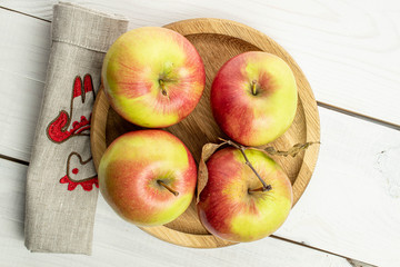 Group of four whole fresh garden apple on wooden plate on white wood