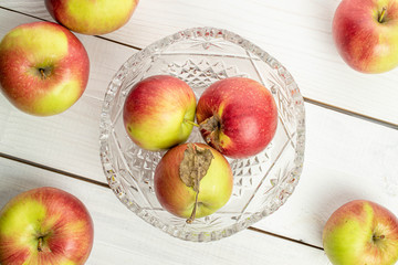 Lot of whole fresh garden apple in crystal bowl on white wood