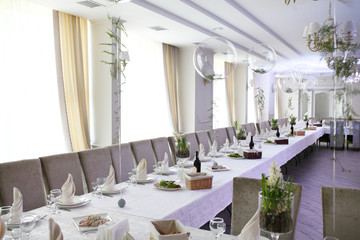 Wedding. Banquet. The chairs and round table for guests, served with cutlery, flowers and crockery and covered with a tablecloth