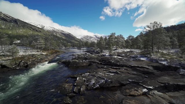 A view of the Gaula river not far from the Likholefossen waterfall. Powerful river carrying its' water down to the valley. Pine forest standing on the riverbanks, wet stones glister in the sun.