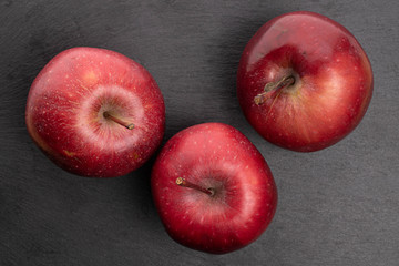 Group of three whole red delicious apple on grey stone