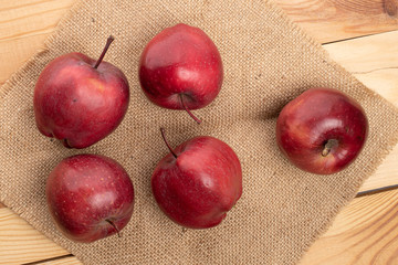 Group of five whole red delicious apple on jute cloth on wood