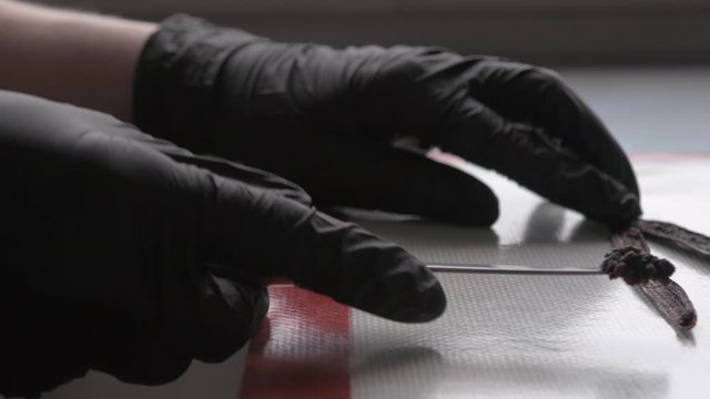 Confectioner with black gloves cutting vanilla
