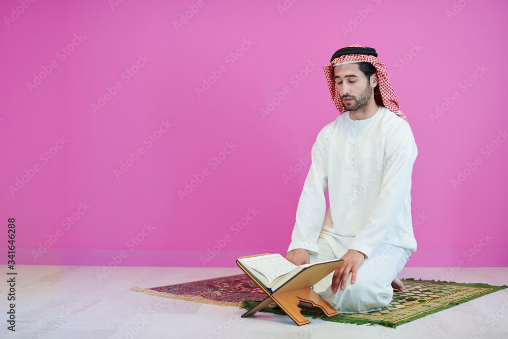 Wall mural young arabian muslim man reading Quran at home