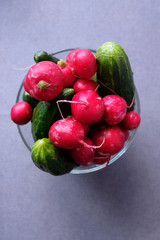 Radishes and cucumbers in a plate on a white background.