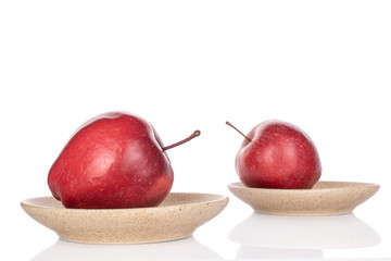 Group of two whole red delicious apple on ceramic plate isolated on white