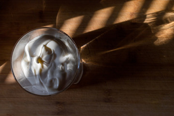 a transparent glass with thick white cream warmly illuminated by a beautiful warm light