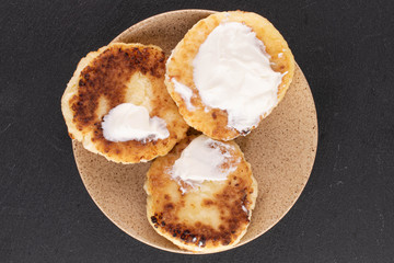 Group of three whole cheese pancake with sour cream on grey stone