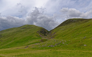 A Water eroded Fault line on the Valley sides of Glen Doll splitting Two Hills, with an old damaged and ruined stone Sheep Pen in the foreground