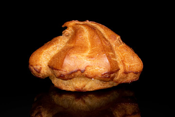 One whole fresh baked profiterole isolated on black glass