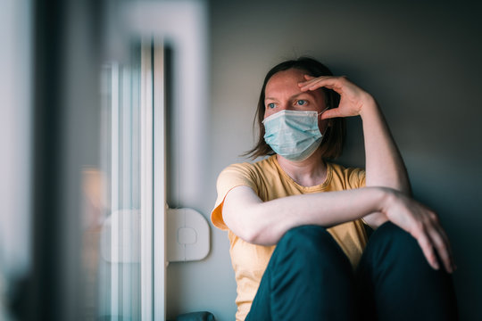 Woman in self-isolation during virus outbreak looking through window