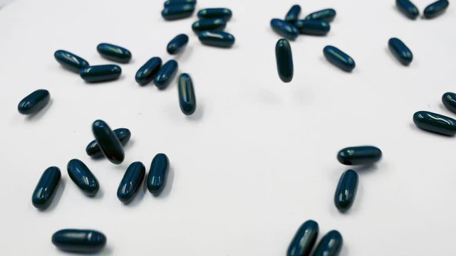 Slow-motion of Blue Medical Pills Fall On white Surface and Table