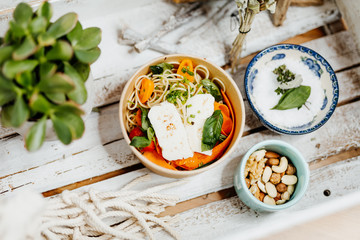Protein-rich food with halloumi, pasta, peppers and carrots in eco box delivered by a delivery service, ordered online, decorated with basil and spices on a white wooden surface
