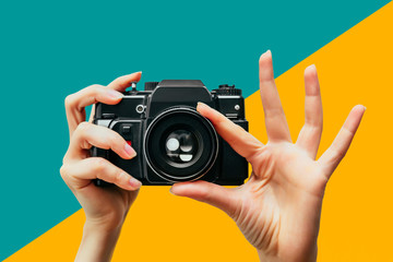Vintage Camera in female hand. A photo. Photographer. Manual focus. Colored background.