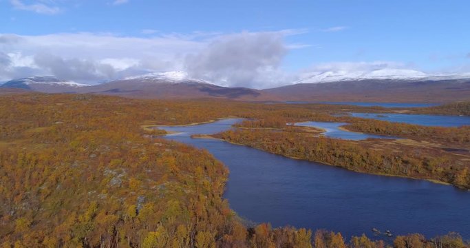 Arctic autumn tundra, Aerial, pan drone shot, overlooking ponds and rocky boreal nature in foliage colors, sunny, fall day, in Lapland, Norrbotten, Sweden