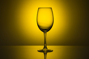 An empty glass goblet on a monochrome background with a spot of light at the back
