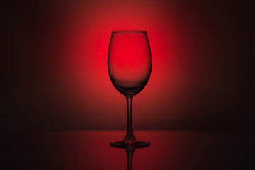 Fototapeta na wymiar An empty glass goblet on a monochrome background with a spot of light at the back