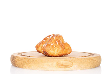 One whole fresh baked profiterole on wooden plate isolated on white