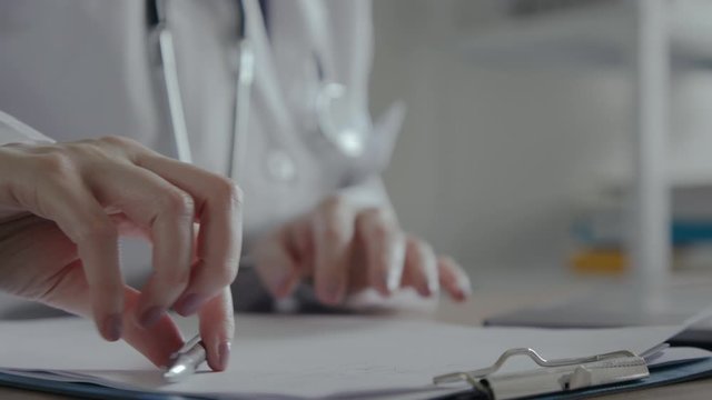 Hand of female doctor taking pen and writing down recommended patient treatment. Medical worker on the job in a hospital office.