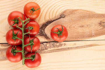 Lot of whole fresh red cherry tomato with vine on wood