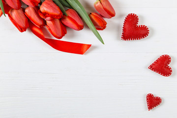 Red tulips and hearts on the white table, background blank for postcards. Copy space.