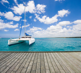 Empty wooden platform with luxury yacht anchored on turquoise water of Caribbean Sea in the...