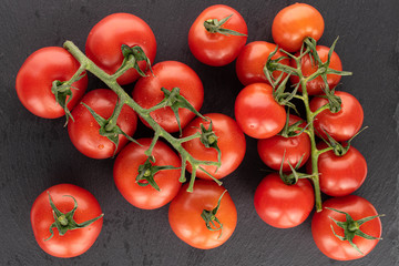 Lot of whole fresh red cherry tomato on grey stone