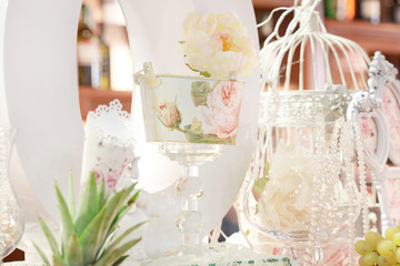 table setting at white wedding reception, floral composition, candles and cones, lights on the background