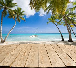 Empty wooden tabletop for Your product advertisement. Tropical beach in Caribbean sea at Saona island in the background, Dominican Republic